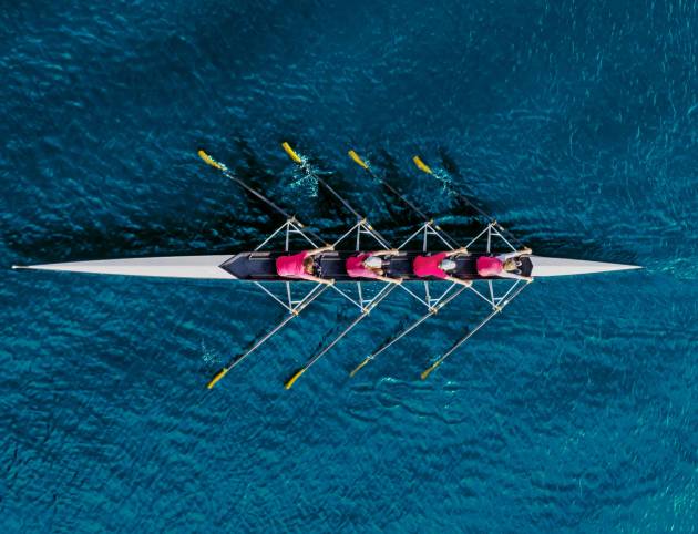 Women's rowing team on blue water, top view