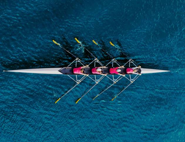 Women's rowing team on blue water, top view